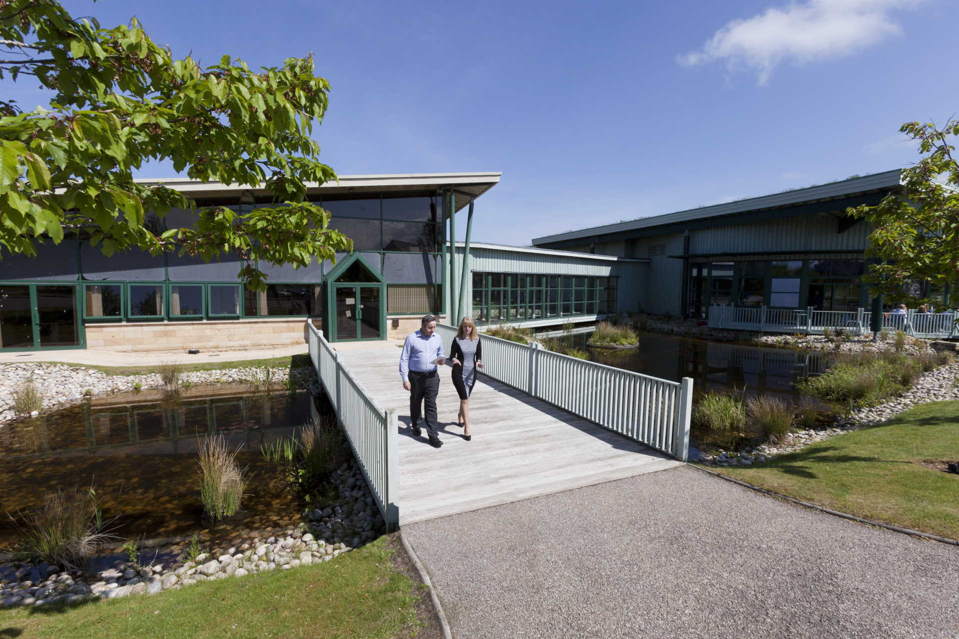 Staff walking over bridge on landscaped gardens at Enterprise Park Forres